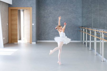 可爱的小女孩穿着白色芭蕾舞鞋,穿着芭蕾舞服和短裙.