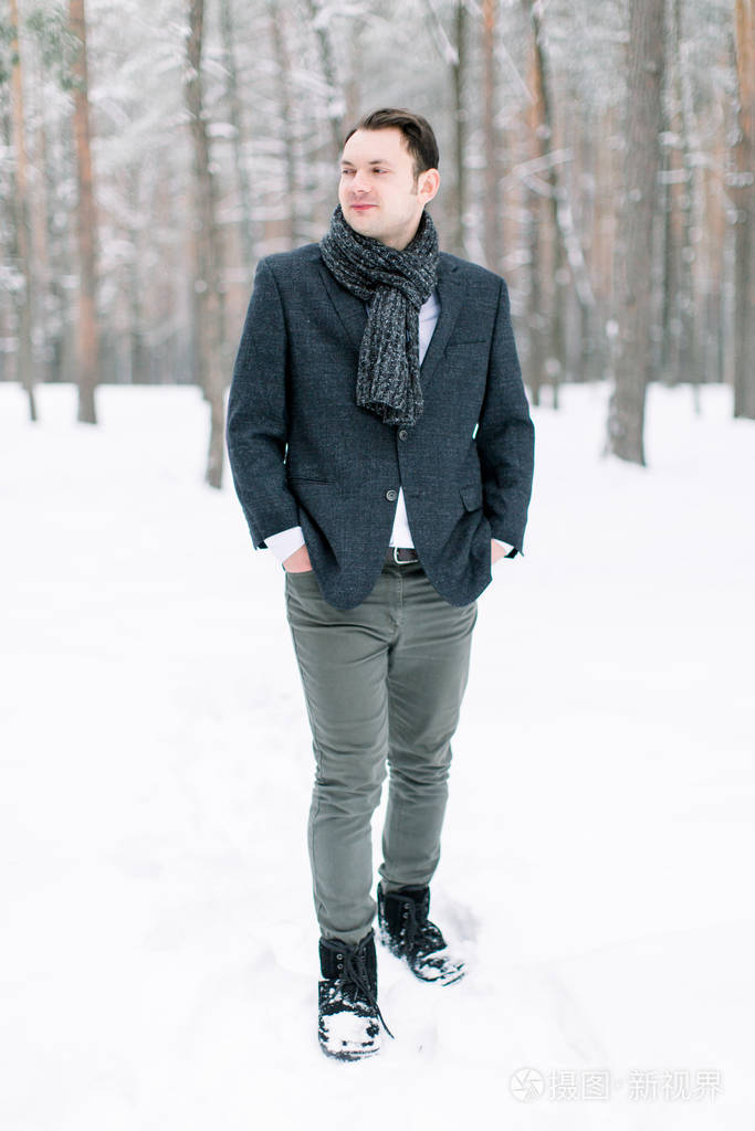 帅气的潮男新郎身穿时尚西装站在冬日雪林中全身合影