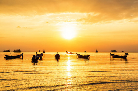 金色夕阳下海上的长尾船剪影。