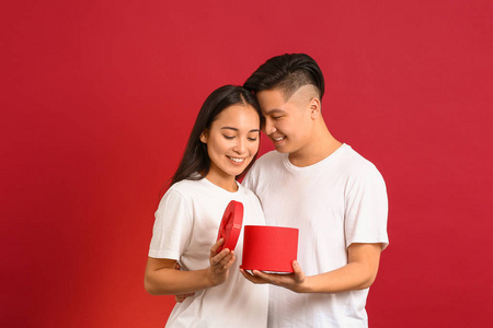 幸福的亚洲年轻夫妇的肖像，彩色背景上有礼物