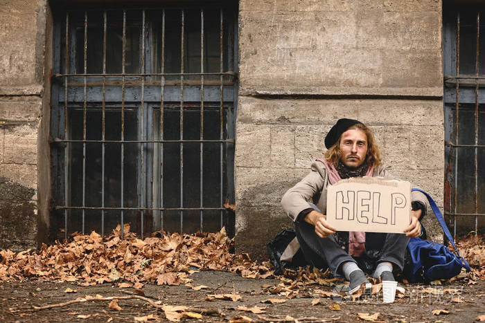 可怜的流浪汉拿着硬纸板在户外发短信