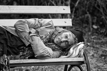 睡在户外长椅上的可怜的无家可归者的黑白肖像