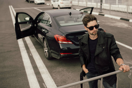  young fashionable man in glasses near the car