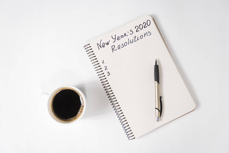 把新年的决心写在笔记本和笔上。桌上一杯咖啡