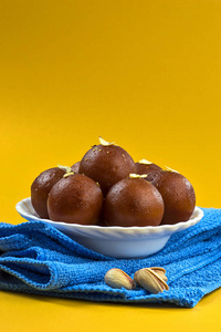 Gulab Jamun，白碗印度甜点，餐巾上有开心果杏仁和腰果