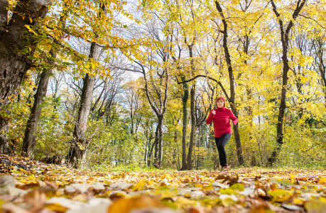 中年妇女穿着运动服在森林里跑步。