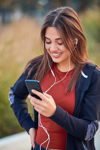 Modern young woman with cellphone making pause during jogging  