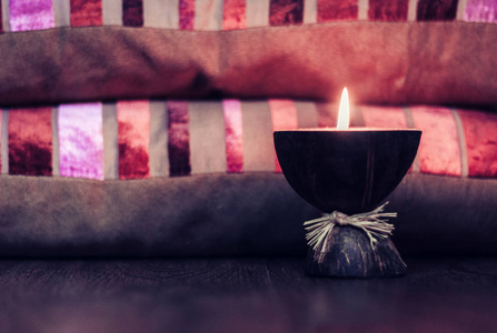 Burning spa aroma candle in coconut shell and  burgundy pillows 