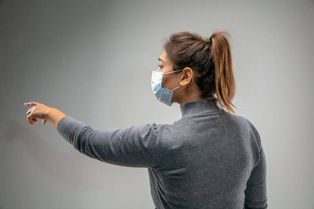 白人妇女戴着呼吸保护面具，以防空气污染和黄昏，背景是灰色的工作室