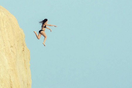 女孩在悬崖附近的空中跳跃。