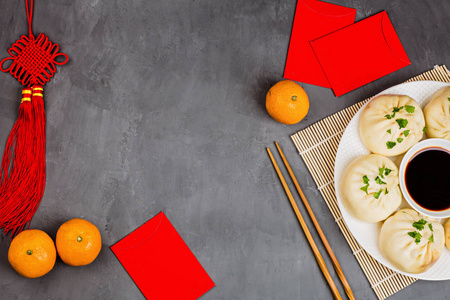 在灰色混凝土背景上用饺子橘子酱油筷子红包装饰春节。2020年春节快乐