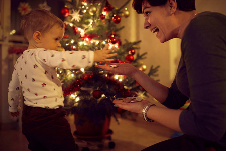 Mother and toddler decorating the Christmas tree 