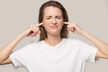 学生烦躁烦躁不开心的女人用手指堵住耳朵,避免大声喧哗照片