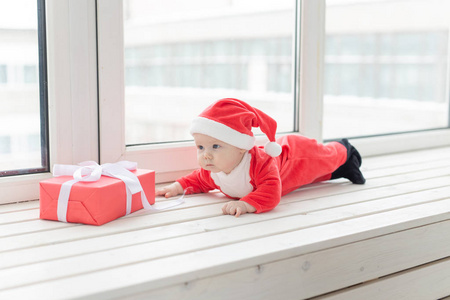 美丽的小宝宝庆祝圣诞节。新年假期。一个穿着圣诞服装戴着圣诞帽的婴儿