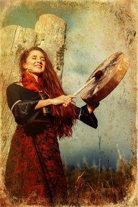 美丽的萨满教女孩在大自然的萨满框架鼓上演奏,古老的efect.照片