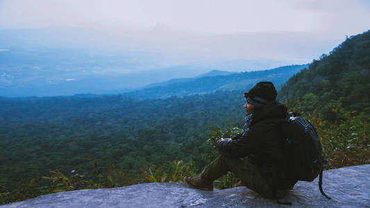 亚洲人旅行自然。旅行放松。坐在悬崖上看自然风景。在山上度假。游览泰国时，欣赏这里的大气景观。