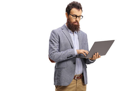 Bearded man with a serious expression working on a laptop 