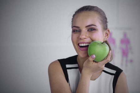 年轻美丽的微笑女孩手拿一个绿色的苹果