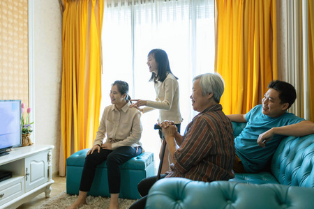 快乐的亚洲家庭,爸爸,妈妈,女儿,和老奶奶放松,在电视上看电影连续剧