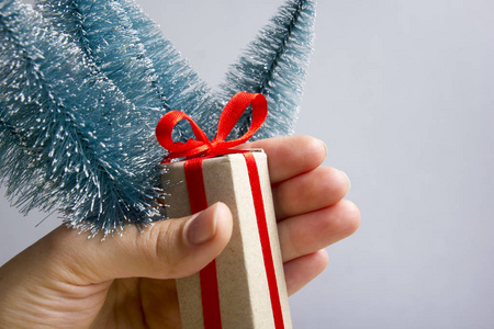 灰色背景下女性手拿礼品盒。圣诞节或新年快乐家庭庆祝概念