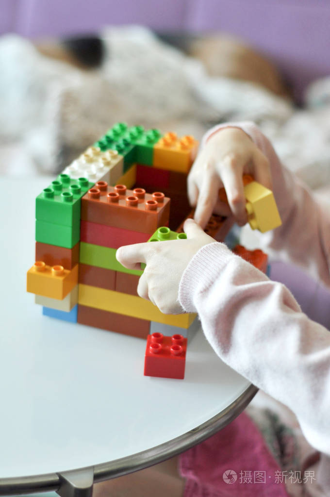 小孩玩塑料色块构装师.特写小女孩手在家里与五颜六色的建筑.有教育玩