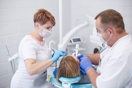 牙医医生给一位年轻漂亮的女病人治疗牙齿。