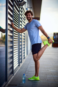 运动员在市区慢跑锻炼时伸展身体。