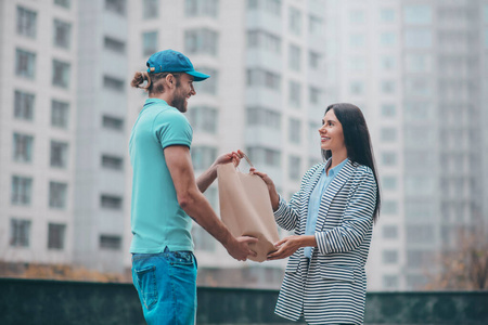 给订单送货员微笑着给顾客带订单的袋子照片