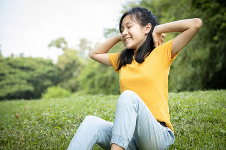 感觉新鲜吗快乐的亚洲女孩在公园里休息感觉很舒服,女青少年双手放在