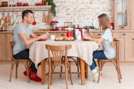 圣诞夜吃早餐的快乐的年轻夫妇