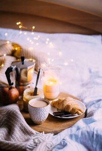 舒适的冬季周末早餐，咖啡和羊角面包放在木制托盘上