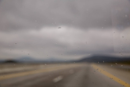 雨滴落在有雾或雾的绿色道路玻璃上。水滴落在车里的玻璃上。雨滴