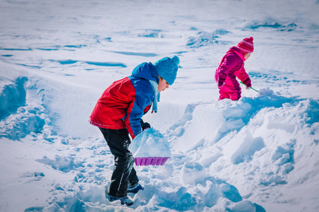 孩子们男孩和女孩在冬天挖雪，孩子们的季节乐趣