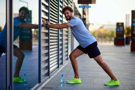 运动员在市区慢跑锻炼时伸展身体。