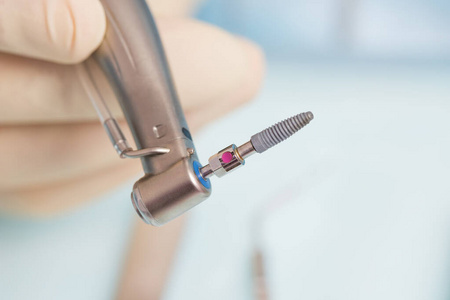 在手术中，牙医拿着植入工具和钛植入物