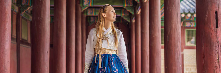 年轻的高加索女游客穿着韩服去韩国旅游。韩国民族服装。游客娱乐试穿韩国国家服装横幅，长格式