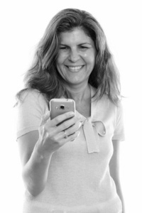 摄影棚拍摄成熟的快乐女人在使用手机时微笑