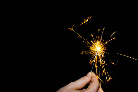 手拿着一根闪闪发光的火柴棒.黑色背景照片