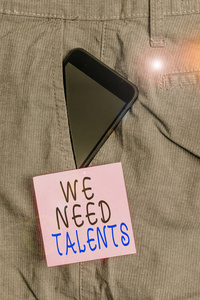 手写文字我们需要人才。概念意义寻找有创意的招聘人员加入公司或团队智能手机设备内正式工作裤前口袋附近的便笺纸。