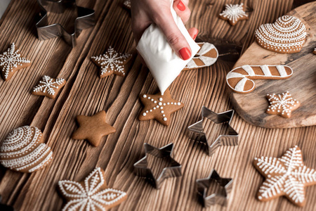 在棕色木质背景上自制姜饼的烹饪过程。星星和心形的圣诞饼干。