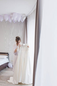 婚礼。新娘穿着漂亮的长袍在家里的人体模特旁边穿着衣服。时尚婚礼风格拍摄。时尚新娘