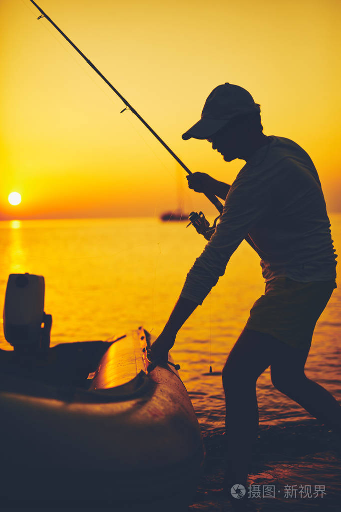 日落时分一个渔夫在公海钓鱼的剪影