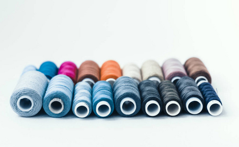 Colored sewing thread coils on white background with copy space 