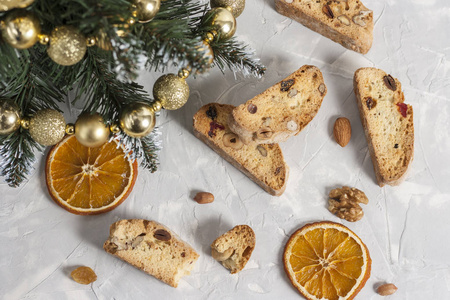 传统的意大利比斯科蒂或坎图奇尼曲奇饼干，有榛子，杏仁，核桃，灰色背景，橘子片和圣诞树。圣诞烘焙的概念