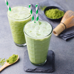 抹茶绿茶冰激凌配抹茶粉和竹打蛋器.灰色背景.闭合.照片