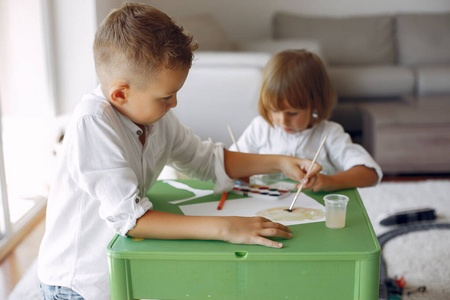 孩子们坐在绿桌子旁画画
