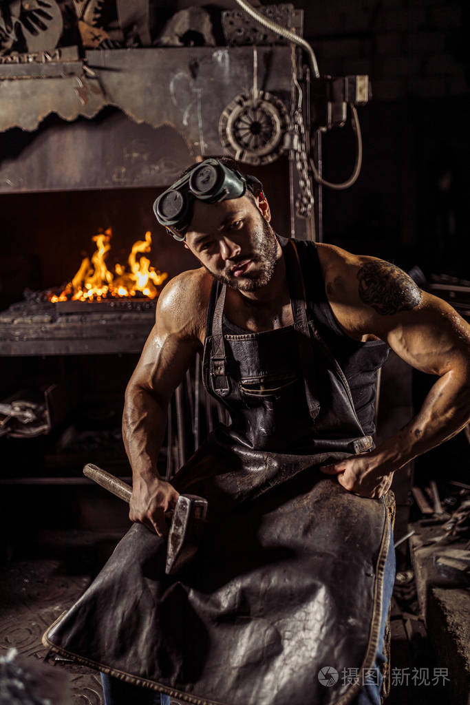 穿着黑色围裙的自信强壮的年轻金属工人肖像