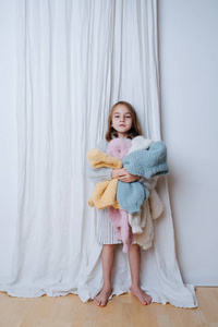 疲惫的小女孩拿着一堆刚洗过的柔软多彩的毛衣
