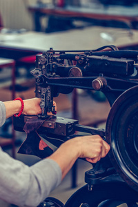 Hands of an experienced seamstress stitching a part of the shoe 