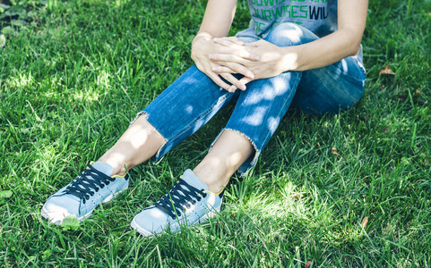 Young woman legs in sport shoes sneakers of blue suede, sitting 